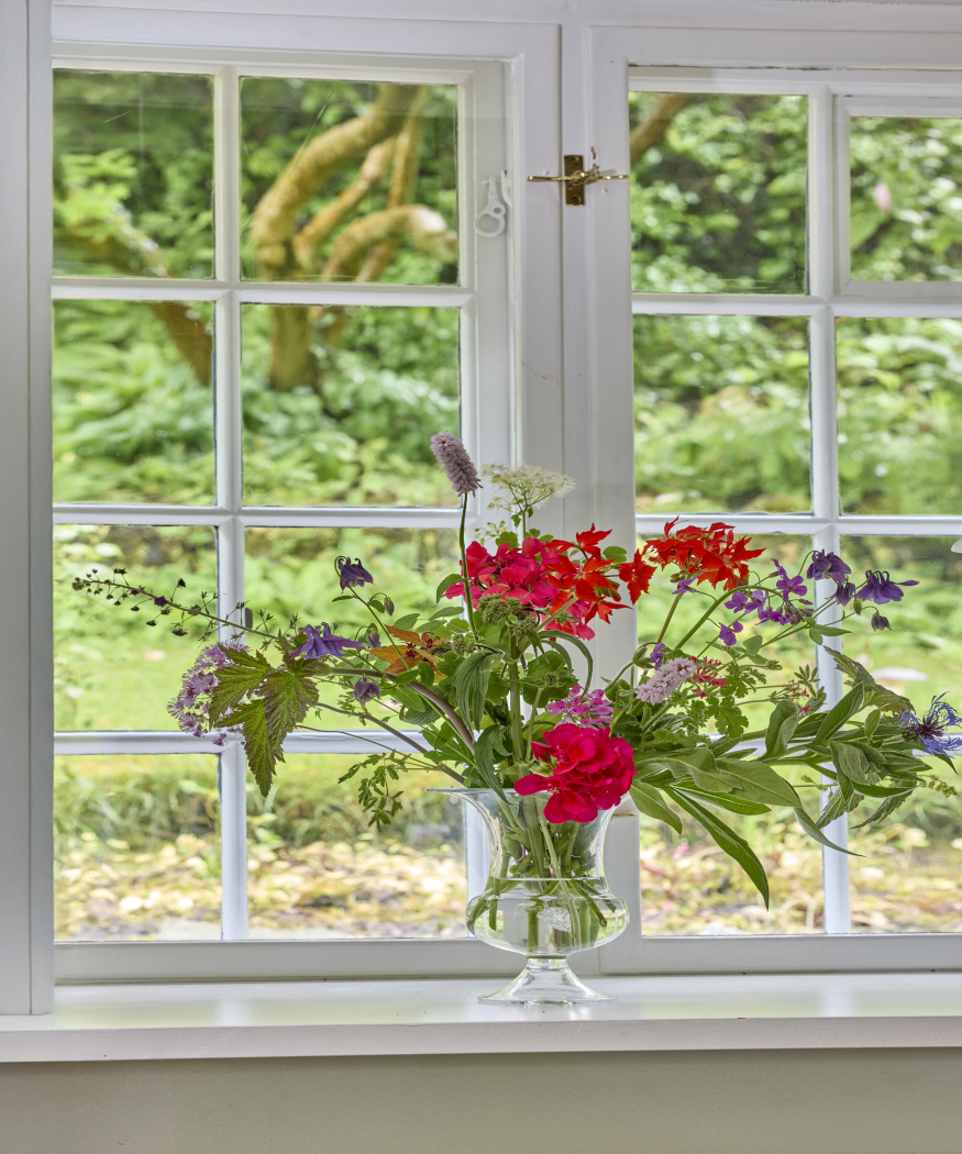 Centres de table avec des géraniums en fleurs coupées.